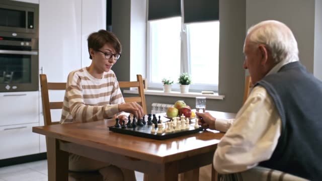 Laughing-Woman-Playing-Chess-with-Senior-Man