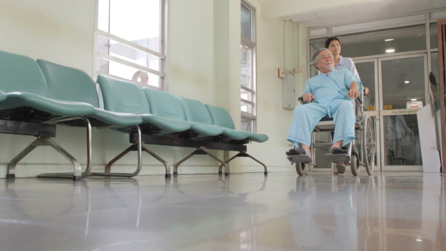 Schöne-asiatische-junge-Frauen-mit-älteren-asiatischen-Männern-Patienten-im-Rollstuhl