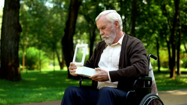 Con-discapacidad-abuelo-mirando-militar-token-en-la-caja-blanca,-Fondo-de-la-patria