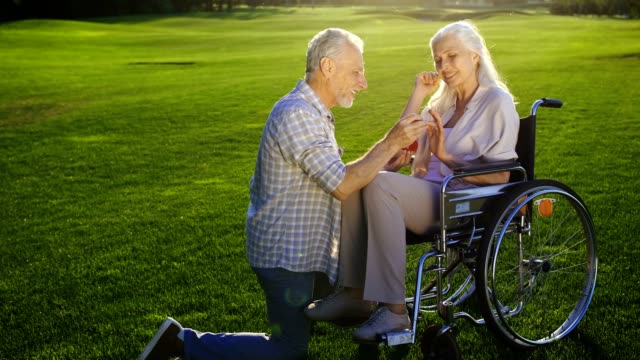 Senior-woman-auf-Knie-schlägt-Frau-im-Rollstuhl