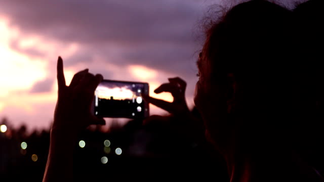 Frau-nehmen-Foto-mit-Sonnenuntergang-Himmel