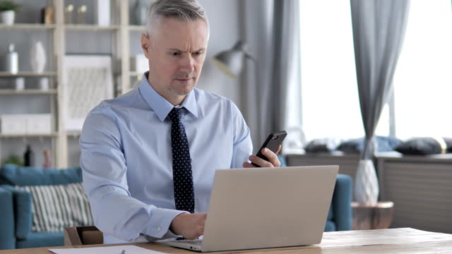 Gray-Hair-Businessman-Using-Smartphone-at-Workplace