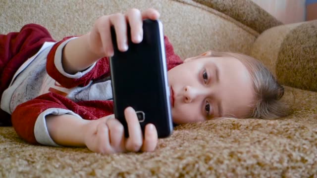 Mädchen-Teenager-sehen-ein-Video-im-Telefon,-während-auf-der-Couch-liegen.