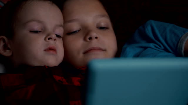 Footage-two-boys-using-tablet-pc-lying-on-sofa.