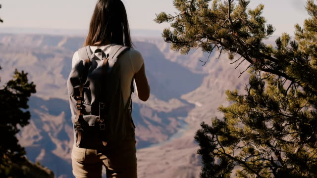 Rückblick-auf-die-glückliche-junge-Touristin,-die-Smartphone-fotografiert-und-die-epische-Bergkulisse-des-Grand-Canyon-in-Arizona-USA-zeigt.
