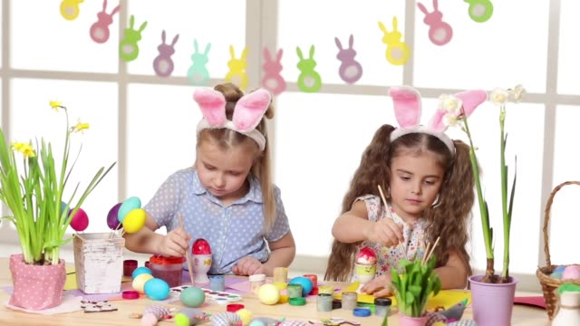 Niños-felices-usando-orejas-de-conejo-pintando-huevos-el-día-de-Pascua.