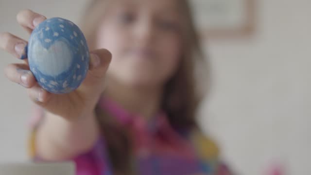 Linda-niñita-sosteniendo-huevo-de-Pascua-azul-con-el-corazón-pintado-en-la-mano