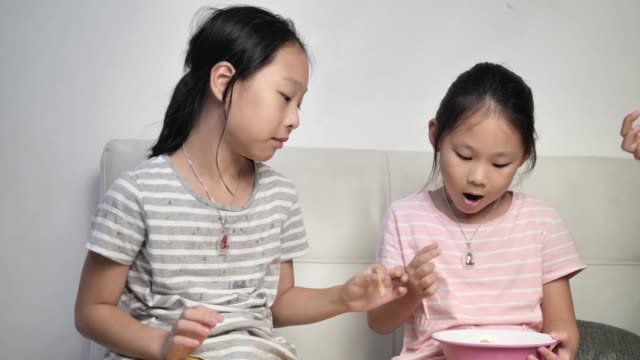 Chica-asiática-feliz-comiendo-papas-fritas-con-la-familia-y-hablando-juntos-en-casa-en-la-noche.