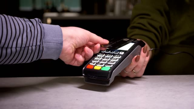 Close-up-shot-of-person-using-terminal-and-credit-card-performs-contactless-payment-and-prints-the-check.
