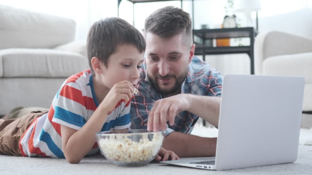 Padre-con-hijo-divirtiéndose-viendo-la-película-en-el-ordenador-portátil