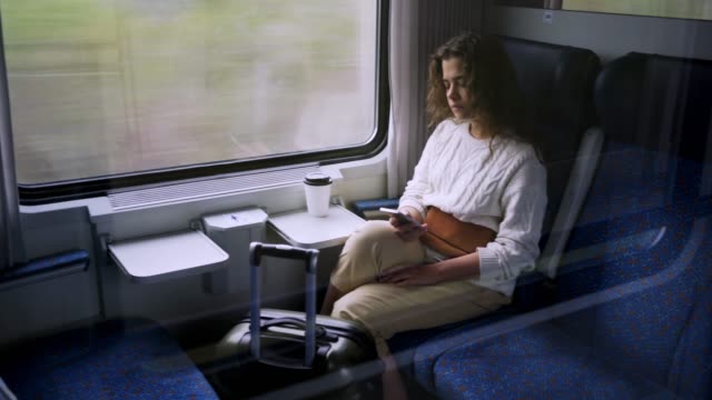 Viajar-en-la-mujer-del-tren-con-teléfono-cerca-de-la-ventana