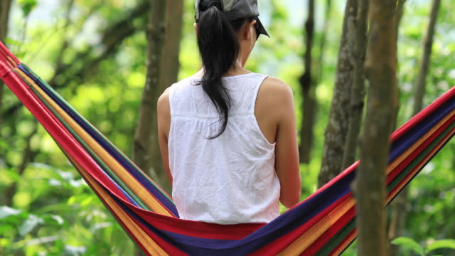 Relaxing-in-hammock-with-smartphone-in-tropical-rainforest