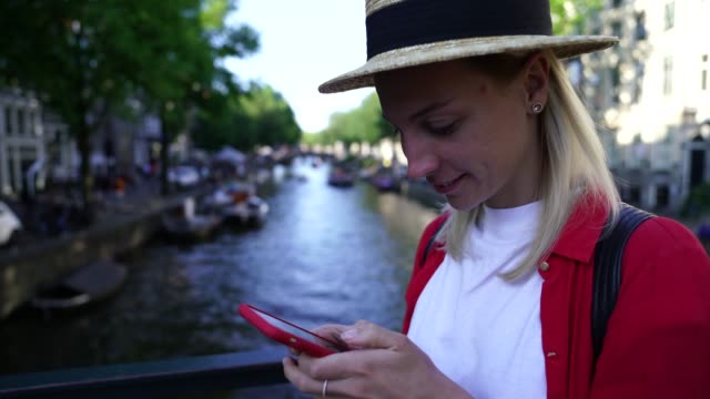 Lächelnde-Touristin-im-Hut-genießen-Reise-nach-Amsterdam-während-der-Sommerferien