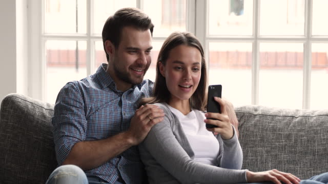 Glückliches-junges-Paar-mit-Smartphone-Social-Media-Apps-zu-Hause