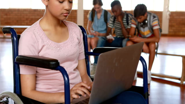 Colegiala-discapacitada-usando-tableta-digital-con-compañeros-de-clase-en-segundo-plano