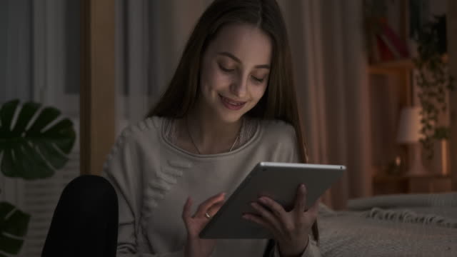 Glücklich-teen-Mädchen-mit-digitalen-Tablet-spät-eabend-im-Schlafzimmer