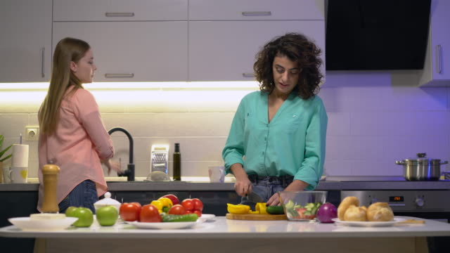 Joven-pareja-de-lesbianas-cocinando-ensalada-de-verduras-en-la-cocina,-pasando-tiempo-juntos