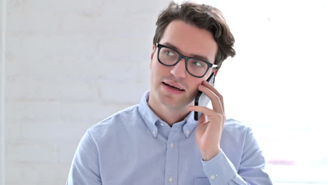 Portrait-of-Cheerful-Young-Man-Talking-on-Smartphone