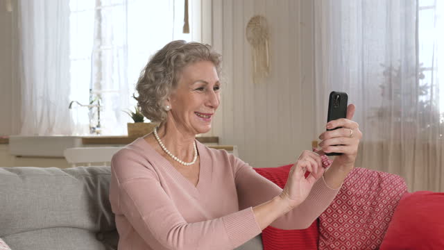Nice-elderly-woman-conducts-video-call-holding-smartphone