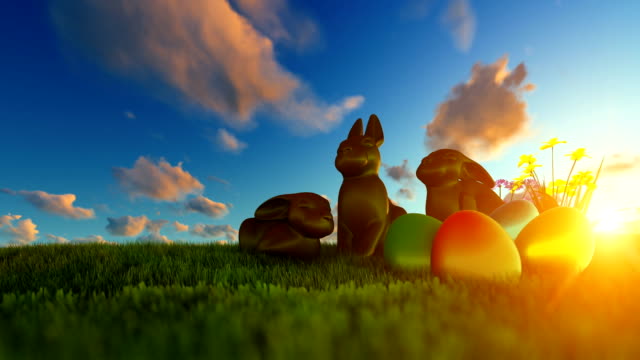 Easter-Eggs-and-Chocolate-Bunnies-on-green-meadow-against-beautiful-sunrise