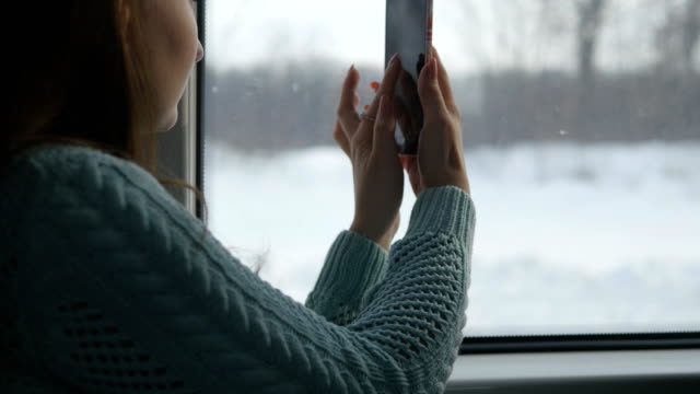 Junges-Mädchen-Reisen-in-einem-Zug-und-Mobiltelefon-zu-benutzen,-nehmen-Sie-ein-Foto-der-Landschaft-vor-dem-Fenster.-Schöne-Frau-nimmt-Bilder-auf-einem-Smartphone.-Nahaufnahme