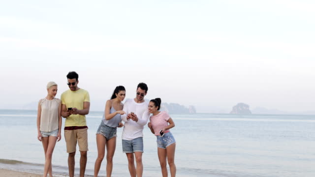 Personas-en-la-playa-usando-celular-teléfonos,-joven-sonriente-grupo-de-turistas-en-línea-de-red-inteligentes