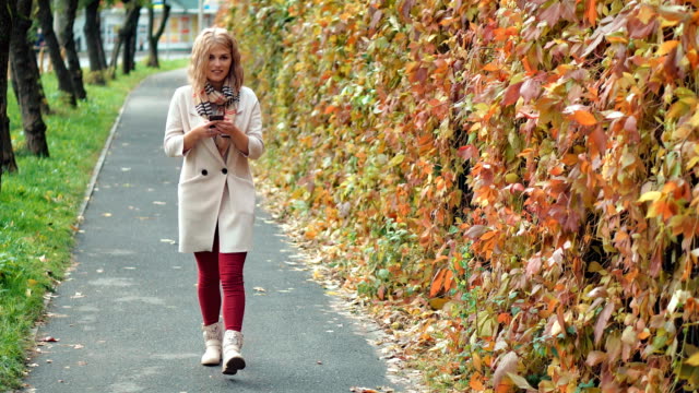 Mujer-joven-con-smartphone-durante-el-paseo-en-el-Parque-otoño