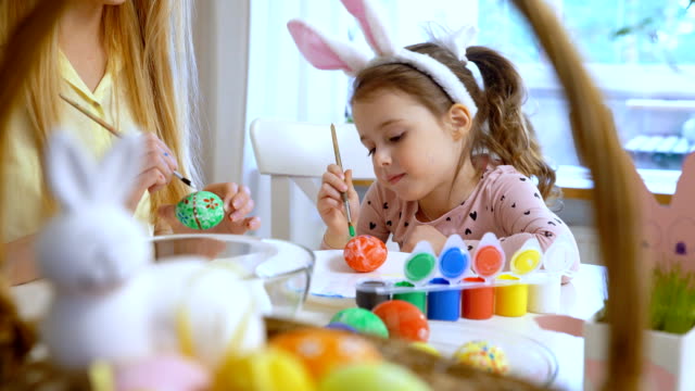 Frohe-Ostern!-Mutter-und-ihre-kleine-Tochter-tragen-lustige-Hasenohren-Ostereier-färben
