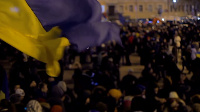 Waving-blue-and-yellow-flag-with-unfocused-crowd-background,-national-symbol