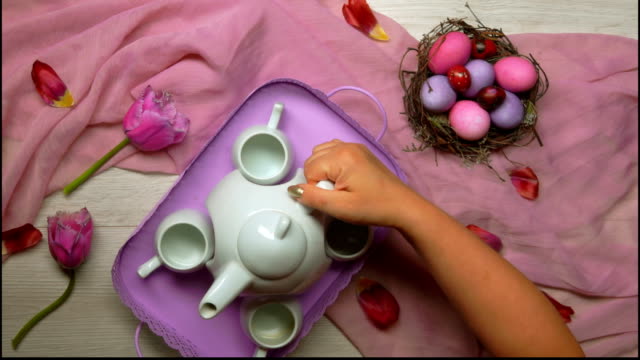 Hände-legen-auf-den-Tisch-ein-Tablett-mit-Tee-auf-dem-Backgroundof-Oster-Nest-mit-Eiern
