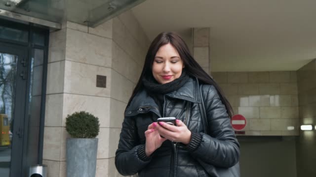 Beautiful-Mixed-race-woman-using-smart-phone-technology-app-walking-through-city-streets-urban-happy