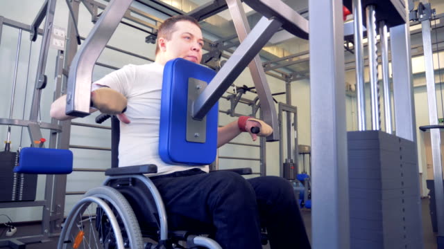 Disabled-man-does-strengths-exercises-for-back-on-training-apparatus.
