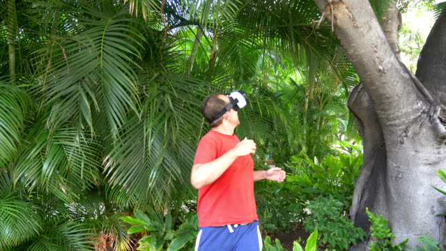 Man-playing-game-in-virtual-reality-glasses-in-tropical-resort-in-4k-slow-motion
