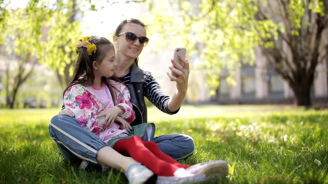 Familia-de-selfie-foto---madre-y-niño-hija-abrazando-besando-a-tomar-fotografías-a-través-de-teléfonos-inteligentes-durante-la-caminata-en-el-Parque