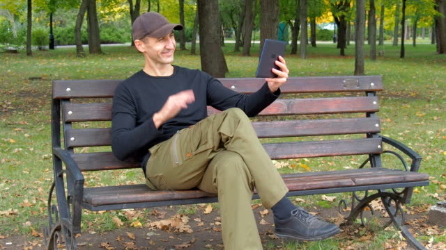 Ein-Mann-in-einem-herbstlichen-Park-mit-einem-tablet