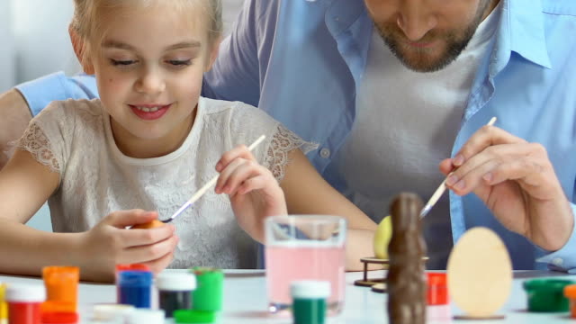 Cheerful-father-and-daughter-preparing-for-Easter,-carefully-painting-eggs