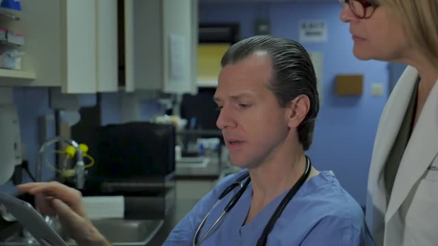 Médico-que-habla-con-una-enfermera-o-un-médico-mientras-mira-una-tableta