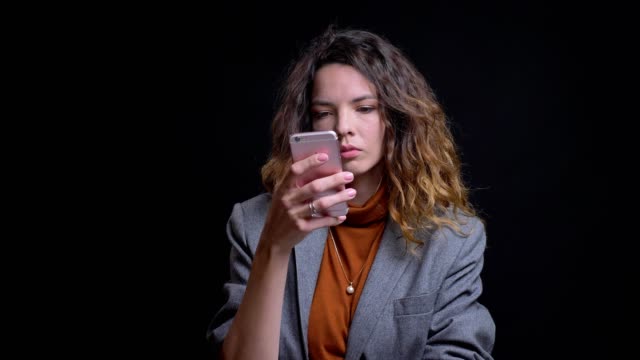 Nahaufhol-Porträt-der-modernen-jungen-Frau,-die-auf-ihrem-Telefon-mit-Blick-auf-Kamera-und-Lachen