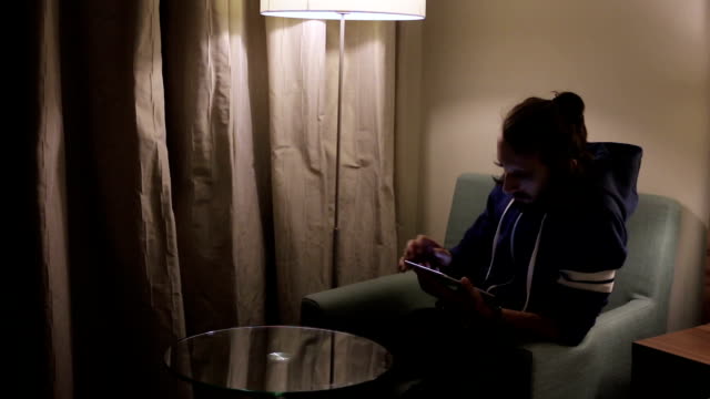 Hübsche,-junge-Mann-mit-Tablet-Computer-auf-Stuhl-zu-Hause-sitzen