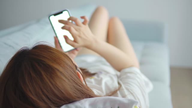 Mujer-asiática-usando-teléfono-celular-en-la-sala-de-estar