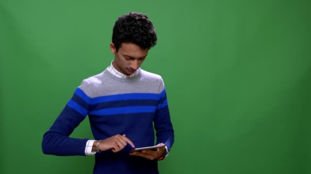Sesión-de-primer-plano-de-joven-indio-atractivo-macho-usando-la-tableta-con-fondo-aislado-en-verde