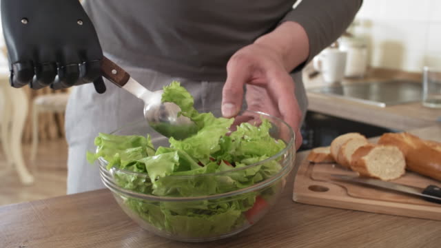 Handicapped-Man-with-Bionic-Forearm-Mixing-Vegetable-Salad-in-Bowl