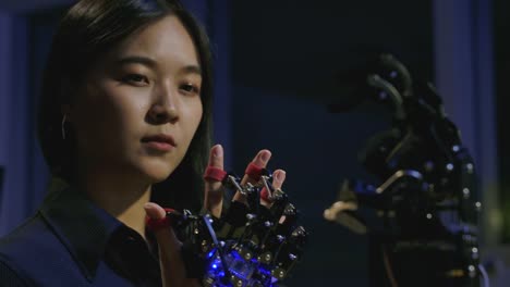 Young-electronics-development-engineers-testing-innovative-robotic-technology-in-laboratory.-Young-asian-female-creates-movement-for-mechanical-robotic-hand.-People-with-technology-or-innovation-concept.
