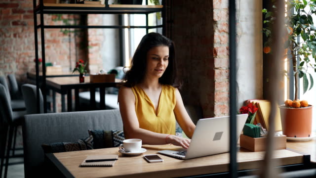 Attraktive-Mädchen-mit-Laptop-in-Café-tippen-lächelnd-arbeiten-in-Café-allein