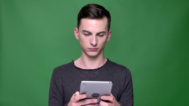 Closeup-shoot-of-young-handsome-caucasian-male-using-the-tablet-with-background-isolated-on-green