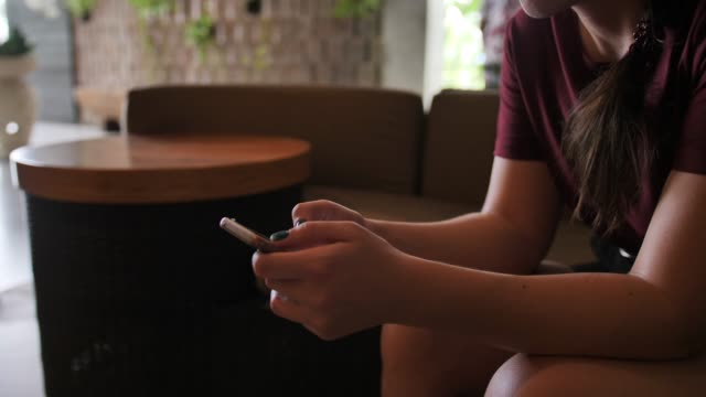 Ein-junges-Mädchen,-das-auf-ein-Hotelzimmer-wartet,-schreibt-in-einem-Chat-auf-einem-Handy