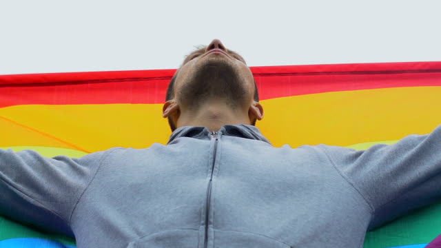 Junger-Mann,-der-Regenbogenflagge-hisst,-LGBT-Rechte,-Solidarität-mit-gleichgeschlechtlicher-Ehe