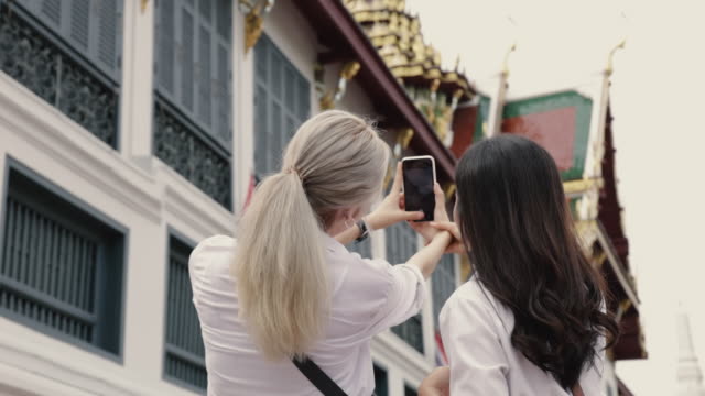 Zwei-Mädchen-asiatische-lesbische-Paare-genießen-Reisen-in-Thailand-und-mit-einem-Smartphone-ein-Selfie.-Schöne-junge-Frauen-mit-Spaß-in-der-Ferienzeit.-LGBT-Konzept.