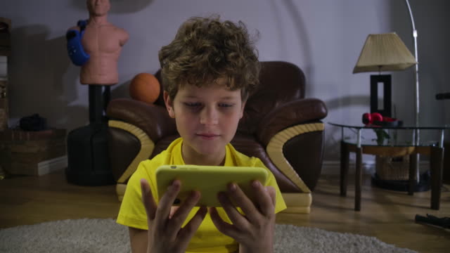 Face-of-focused-Caucasian-boy-watching-cartoons-or-movie-on-smartphone-screen.-Child-with-curly-hair-absorbed-by-internet.-Social-media,-modern-technologies.-Cinema-4k-ProRes-HQ.