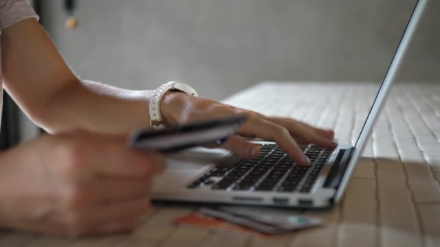 Primer-plano-de-mujer-comprando-en-línea-usando-el-ordenador-portátil-con-tarjeta-de-crédito